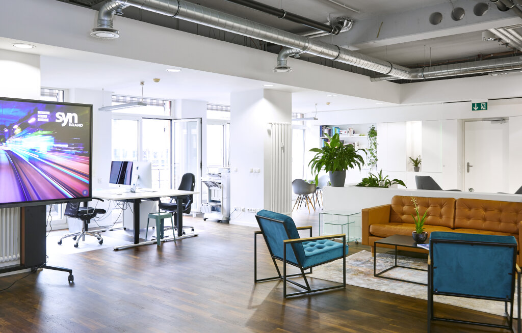 Helle, moderne B&uuml;ror&auml;ume von SYNBRAND in M&uuml;nchen mit offenen Arbeitspl&auml;tzen und gem&uuml;tlichem Besprechungsbereich.