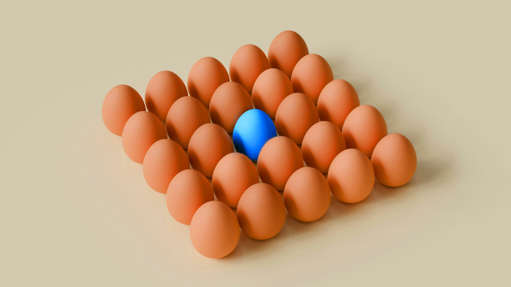 Ein blaues Ei liegt inmitten vieler brauner Eier.