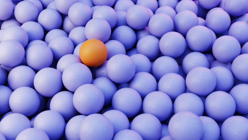 Eine orange Kugel liegt zwischen dicht gepackten violetten Kugeln.